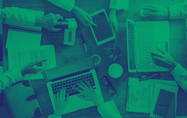 Une équipe collabore autour d'une table avec des ordinateurs portables, des tablettes et de la paperasse